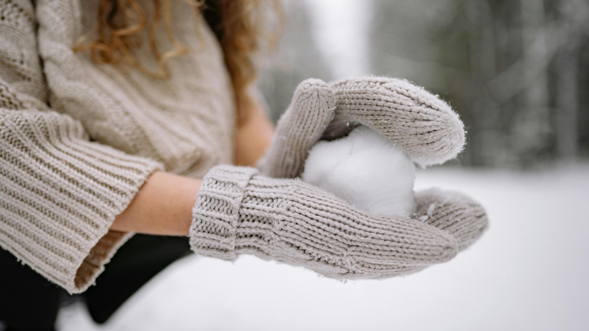 women wearing winter gloves making a snowball