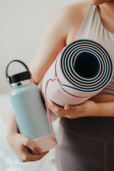 woman carrying yoga mat and water bottle
