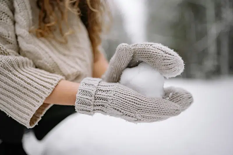 women wearing winter gloves making a snowball