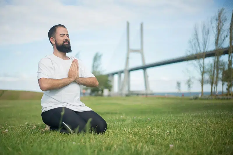 adult man meditating in the grass